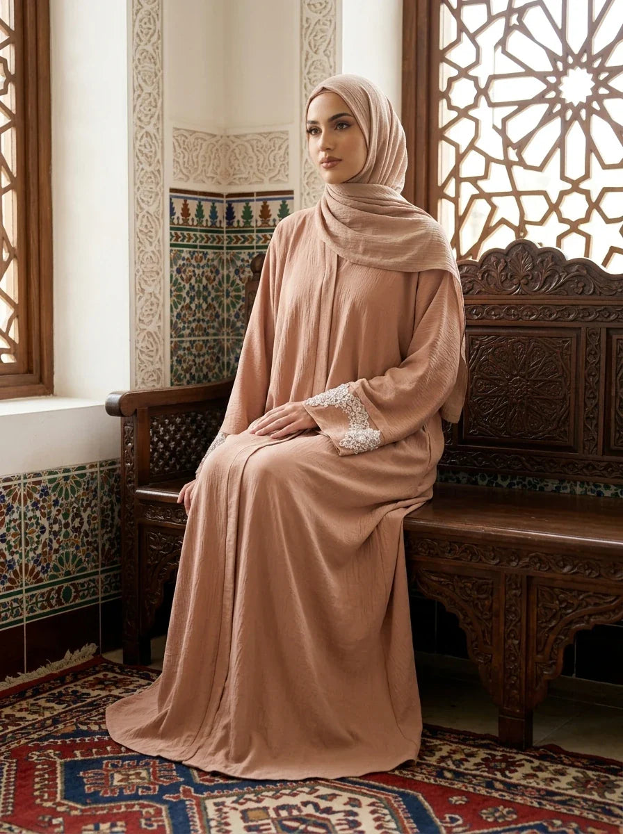Model seated on wooden bench wearing pink Aleena Abaya