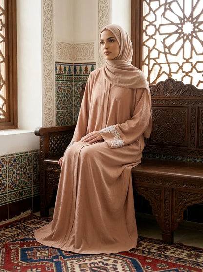 Model seated on wooden bench wearing pink Aleena Abaya