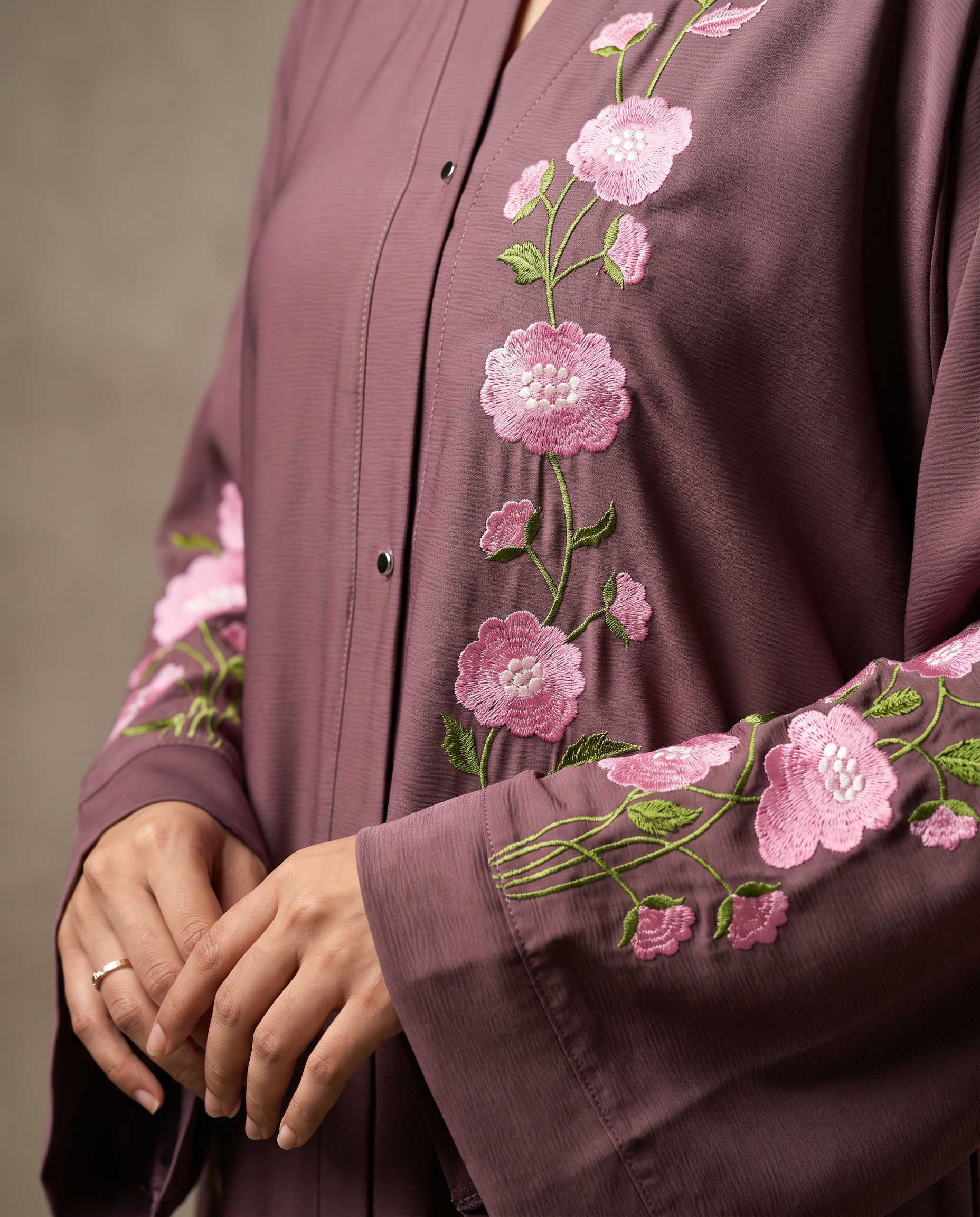 Close-up of hand-embroidered pink floral detail on Zainab Abaya's mauve Nida sleeve and placket